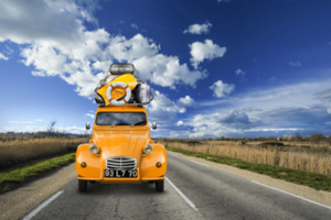 Una C2 arancione carica di bagagli viaggia su una strada deserta sotto il cielo azzurro