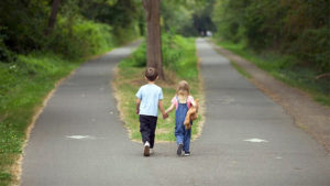 Due bambini si tengono per mano davanti ad un bivio