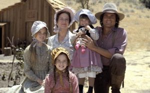 Papà, mamma, le tre figlie della famiglia Ingalls e sullo sfondo la loro casa nella prateria