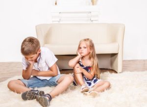 Fratello e sorella arrabbiati seduti sul tappeto del salotto