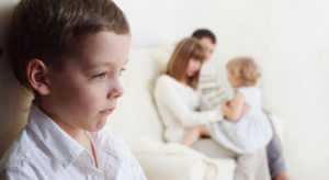 Un bambino e sullo sfondo mamma papà e la sorellina di cui essere geloso