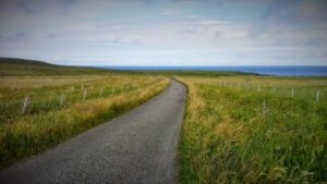 Una strada che attraversa una collina e sullo sfondo il mare