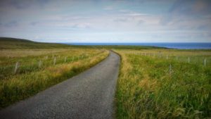 Una strada che attraversa una collina e sullo sfondo il mare