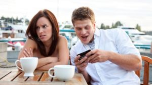 Un ragazzo che guarda lo smartphone con accanto una ragazza completamente disinteressata