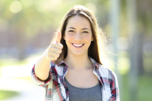 Una ragazza felice di essere una ragazza alfa e sorridente alza il pollice con assertività