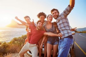 Un gruppo di giovani organizzata una gita al mare si fanno un selfie felici