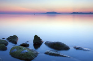 L'inizio del tramonto sul lago e in primo piano delle rocce