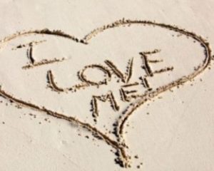 La scritta I love me dentro ad un cuore disegnato sulla sabbia