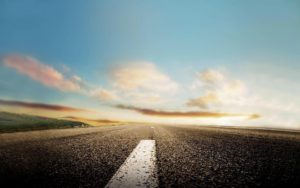 Una strada asfaltata con la linea bianca di mezzeria e il tramonto sullo sfondo