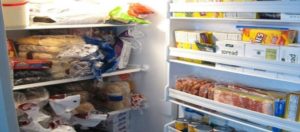 Un frigorifero aperto troppo pieno di alimenti per giunta spazzatura