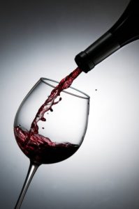 Una bottiglia di vino rosso sta versando in un calice