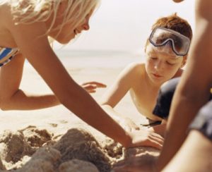 Una mamma costruisce castelli di sabbia in riva al mare col suo bambino