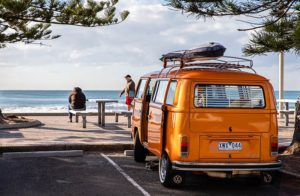 Un van color arancione parcheggiato in riva al mare