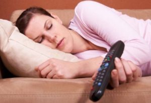 Una donna dorme in divano col telecomando in mano