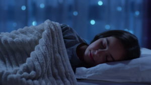 Una ragazza dorme serena con buio e temperature adeguate e sullo sfondo un bel blu con stelle