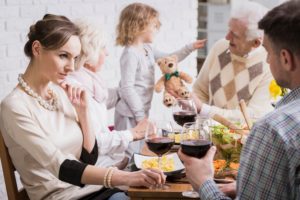 Una moglie guarda significativamente suo marito e sullo sfondo suoceri e nipotina