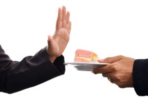 Una mano offre insistentemente una fetta di torta e un'altra mano dice fermamente di no senza sensi di colpa