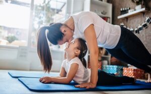 Una mamma con la sua bambina vivono il lockdown in famiglia facendo ginnastica insieme in soggiorno
