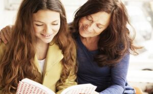 Una ragazza sorridente legge un libro con accanto sua madre