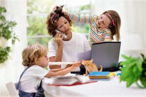 Una mamma vive conflittualità da prevenire essendo in smart working perché lavora da casa col suo computer circondata dai figli che giocano e dal gatto