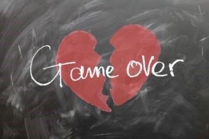 Una lavagna nera con disegnato un cuore rosso spezzato in due e la scritta bianca game over