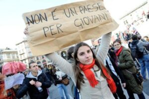 In una manifestazione giovanile una ragazza porta il cartello "non è un paese per giovani"