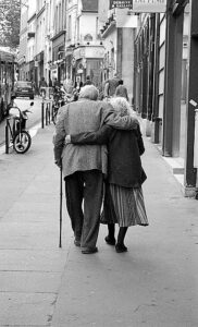 Un uomo ed una donna anziani di spalle camminano insieme sorreggendosi l'un l'altra