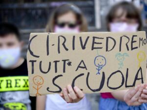 Una ragazzina con masherina e cartello per il mancato ultimo giorno di scuola del 2020