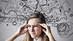 Una donna con le mani alle tempie e gli occhi stretti per lo stress causato dall'ingorgo cognitivo ed emotivo