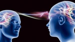 Due cervelli collegati da un fascio di luce nel buio rappresentante i neuroni specchio e l'empatia