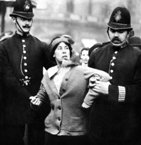 Una "Suffragetta" arrestata da due poliziotti durante una manifestazione per i diritti delle donne